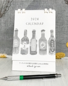A6縦ほどの卓上カレンダーの写真。表紙のデザインは、モノクロ水彩風のタッチで様々なラベルのビール瓶が5本描かれているイラスト。上部にテキスト「2024 カレンダー」。